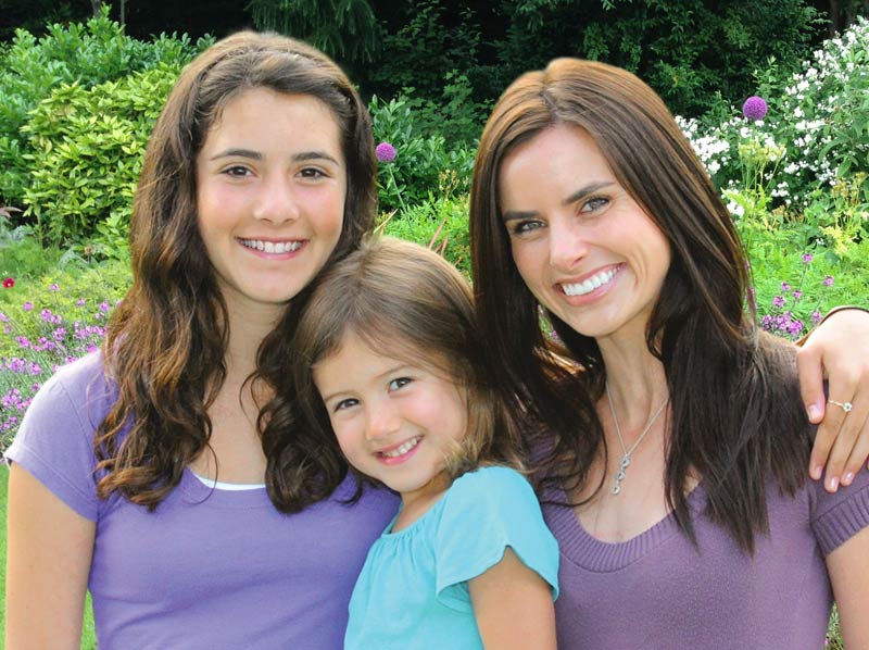 Mother and two daughters smiling and enjoying the outdoors.